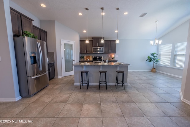 kitchen with pendant lighting, light tile patterned floors, stainless steel appliances, and vaulted ceiling