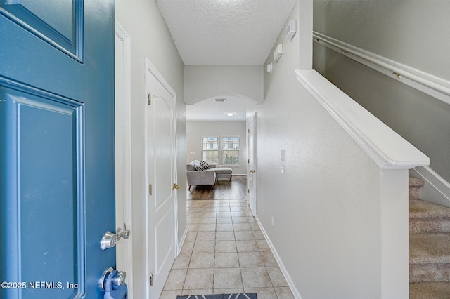 corridor featuring light tile patterned floors and a textured ceiling