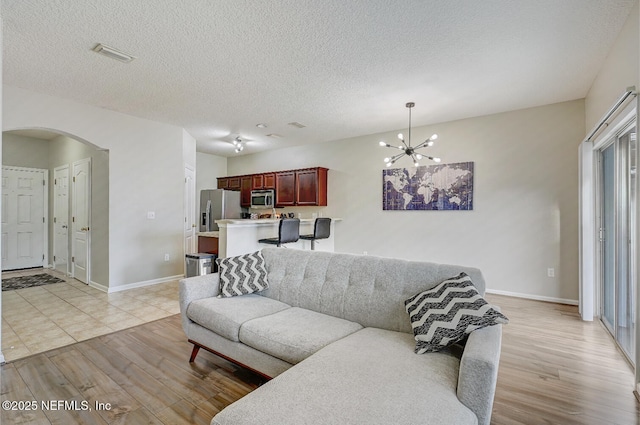 living room featuring a notable chandelier, light hardwood / wood-style floors, and a textured ceiling