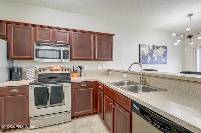 kitchen with a textured ceiling, stainless steel appliances, sink, a notable chandelier, and light tile patterned flooring