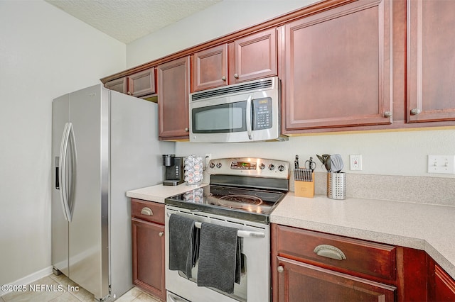 kitchen featuring light tile patterned floors, a textured ceiling, and appliances with stainless steel finishes