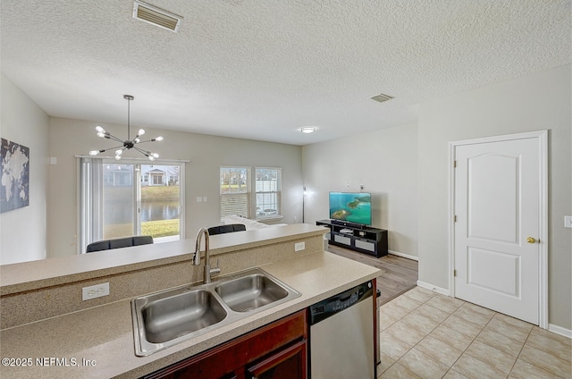 kitchen with stainless steel dishwasher, a textured ceiling, sink, a notable chandelier, and hanging light fixtures