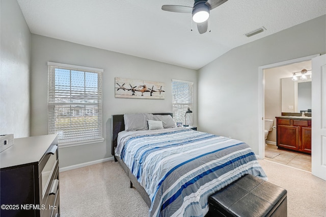 bedroom featuring connected bathroom, ceiling fan, light colored carpet, and vaulted ceiling