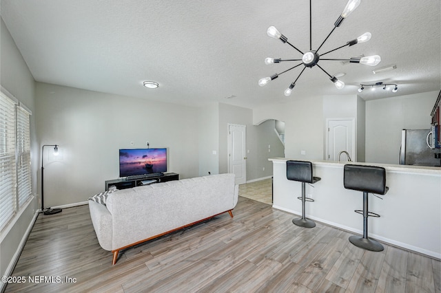 living room featuring light hardwood / wood-style flooring, a textured ceiling, and a notable chandelier