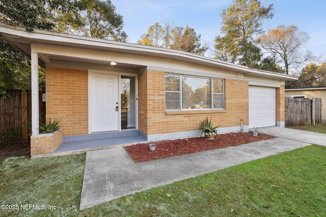 view of front of house with an attached garage, brick siding, fence, driveway, and a front lawn