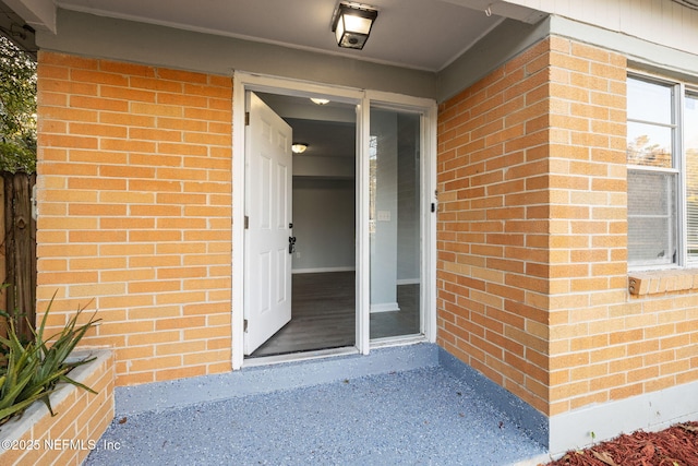 view of exterior entry featuring brick siding