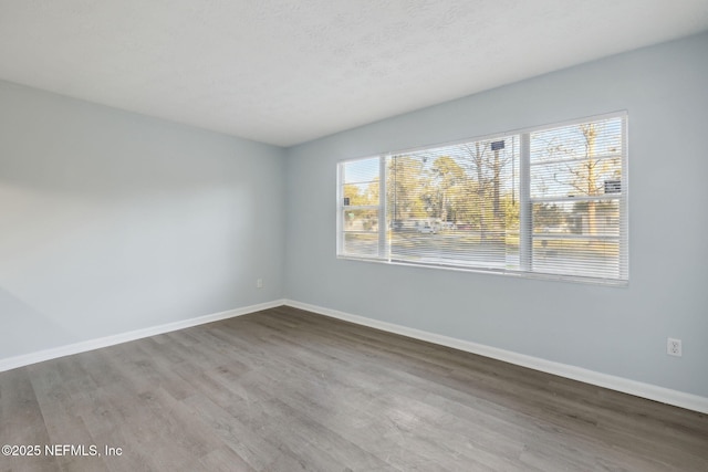 spare room featuring a textured ceiling, baseboards, and wood finished floors