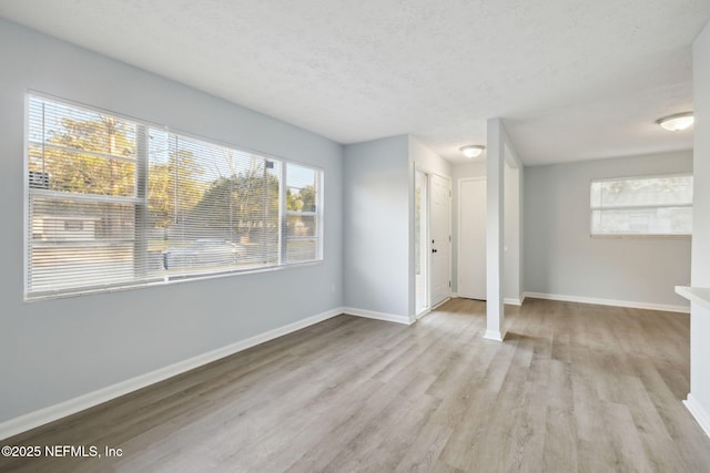 interior space featuring light wood-style flooring, baseboards, and a textured ceiling