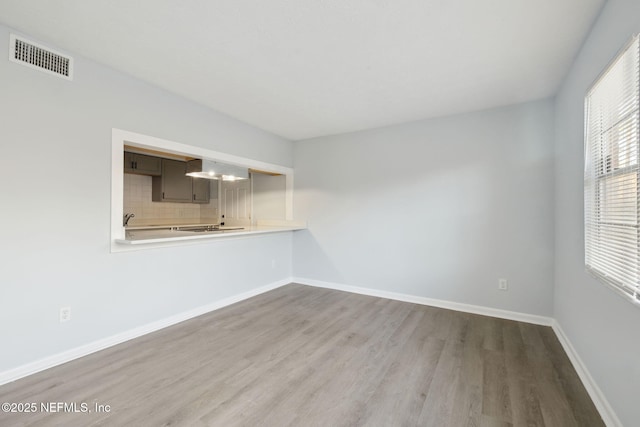 spare room with light wood-type flooring, visible vents, and baseboards