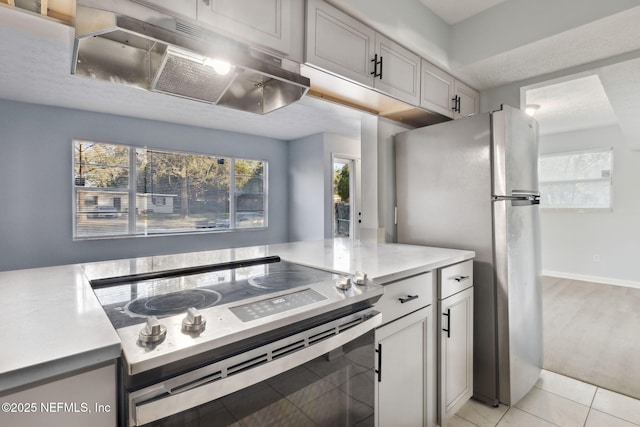 kitchen with light tile patterned floors, appliances with stainless steel finishes, light countertops, gray cabinetry, and under cabinet range hood