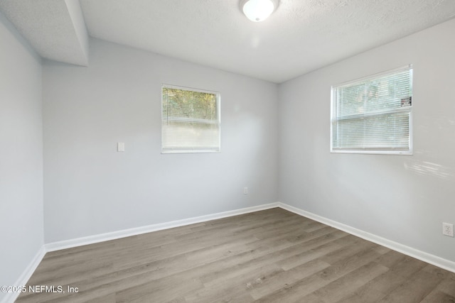 spare room with plenty of natural light, baseboards, and wood finished floors