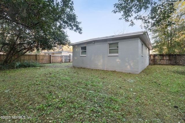 rear view of house with a yard and a fenced backyard