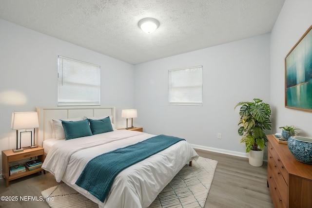 bedroom featuring a textured ceiling, baseboards, and wood finished floors