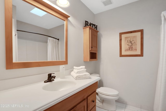 bathroom featuring a skylight, walk in shower, tile patterned floors, toilet, and vanity