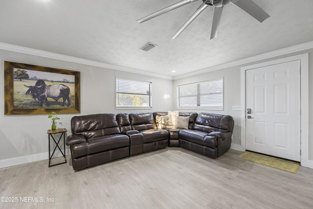 living room with a textured ceiling, light wood-type flooring, ceiling fan, and ornamental molding