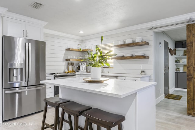 kitchen with a breakfast bar, appliances with stainless steel finishes, a center island, and white cabinets