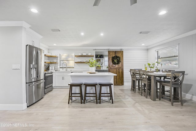 kitchen with a breakfast bar area, white cabinetry, a kitchen island, and stainless steel appliances