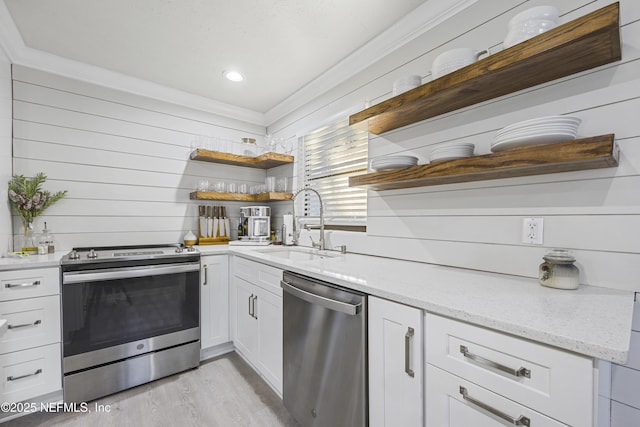 kitchen with white cabinetry, sink, stainless steel appliances, light stone counters, and light wood-type flooring