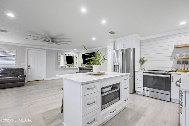 kitchen with light stone countertops, appliances with stainless steel finishes, crown molding, white cabinets, and a kitchen island