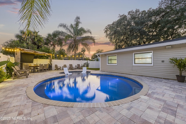 pool at dusk featuring a patio