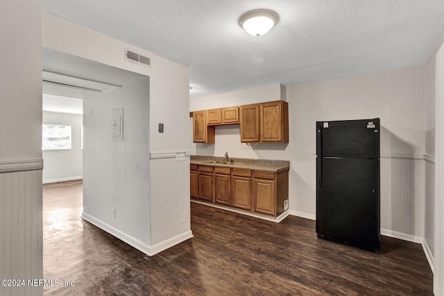 kitchen with black fridge, dark hardwood / wood-style flooring, sink, and a textured ceiling