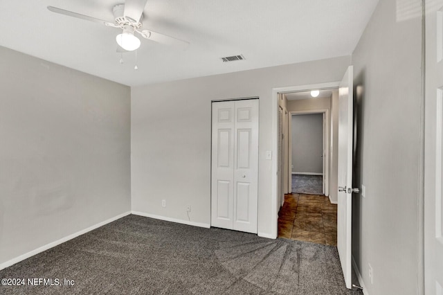 unfurnished bedroom with ceiling fan, a closet, and dark colored carpet