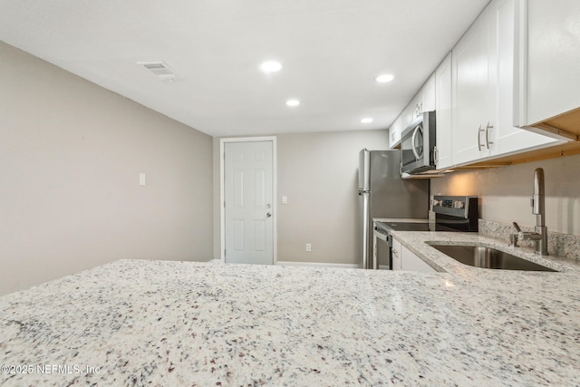 kitchen featuring sink, light stone counters, white cabinetry, and stainless steel appliances