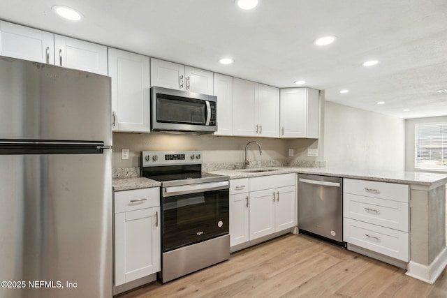 kitchen featuring kitchen peninsula, white cabinetry, stainless steel appliances, and light hardwood / wood-style floors