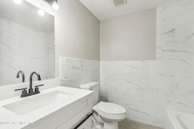 bathroom featuring vanity, a bath, tile walls, and toilet