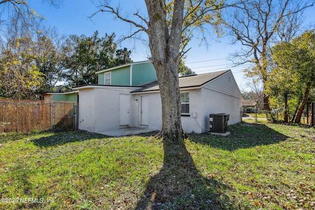 back of property with central AC and a lawn