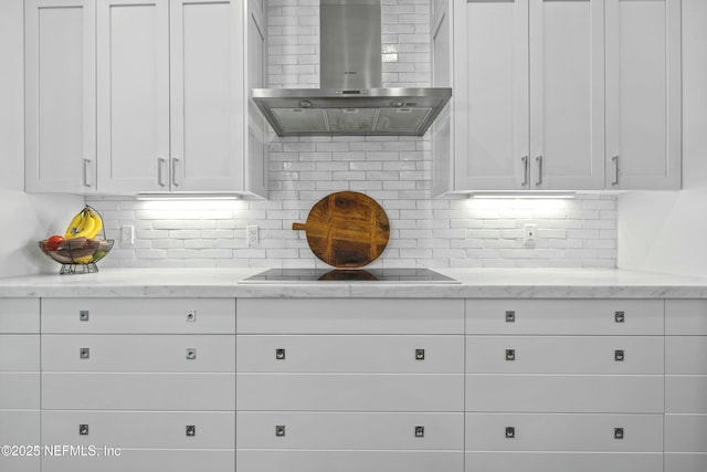 kitchen with backsplash, wall chimney exhaust hood, light stone countertops, and white cabinets