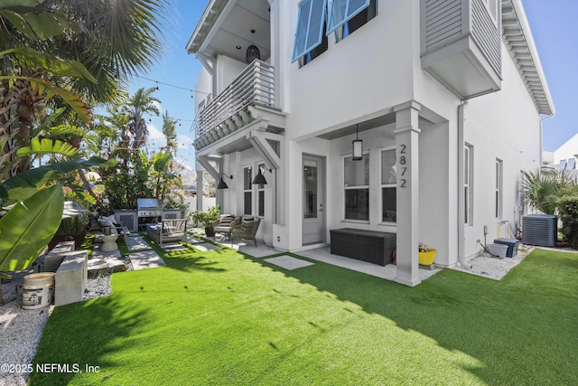 back of house with a patio area, a balcony, central AC unit, and a lawn