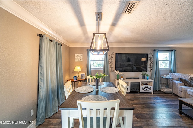 dining room featuring dark hardwood / wood-style floors, a textured ceiling, and ornamental molding