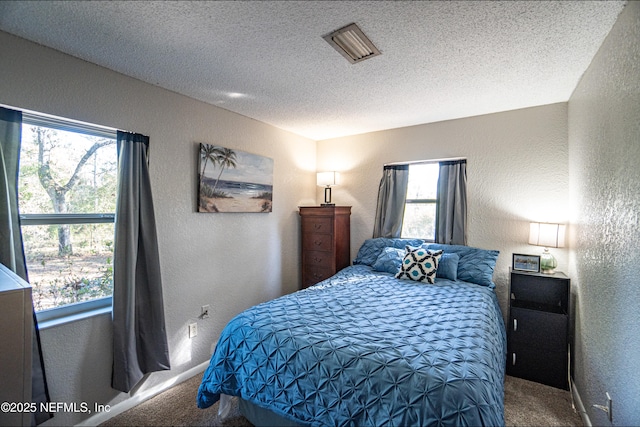 bedroom with multiple windows, carpet floors, and a textured ceiling