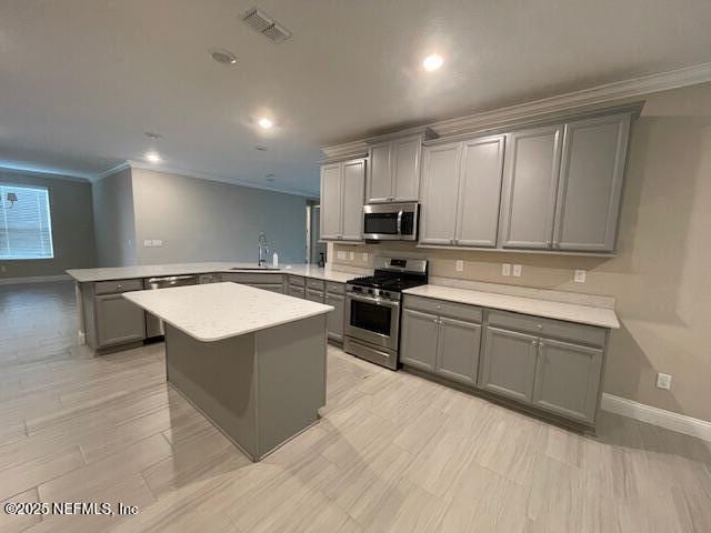 kitchen with sink, stainless steel appliances, kitchen peninsula, crown molding, and gray cabinets