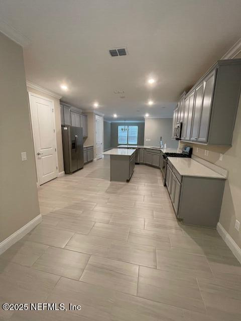 kitchen with kitchen peninsula, appliances with stainless steel finishes, gray cabinets, and ornamental molding