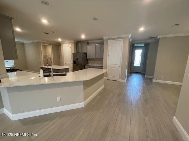 kitchen with a spacious island, crown molding, sink, stainless steel refrigerator with ice dispenser, and gray cabinets