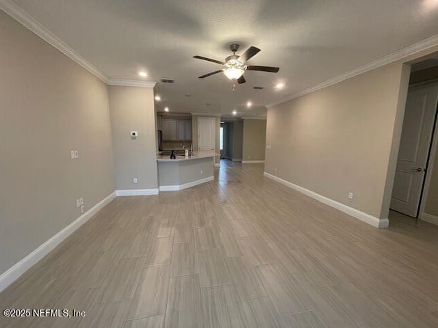 unfurnished living room with ceiling fan and ornamental molding