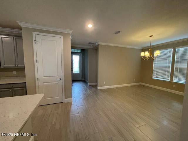 unfurnished dining area featuring light hardwood / wood-style floors, ornamental molding, and a notable chandelier