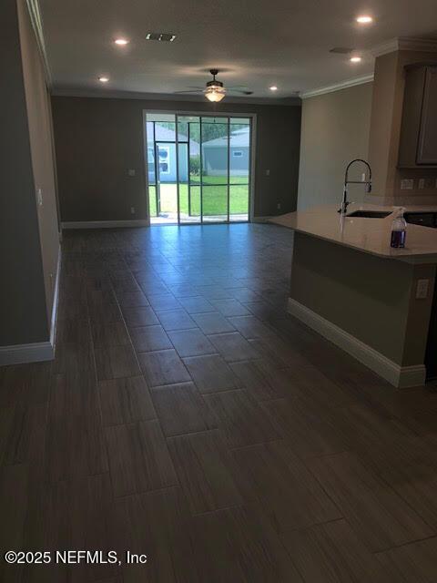 unfurnished living room featuring ceiling fan and sink