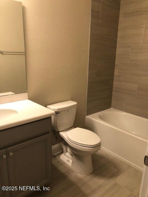 full bathroom with bathing tub / shower combination, vanity, and toilet