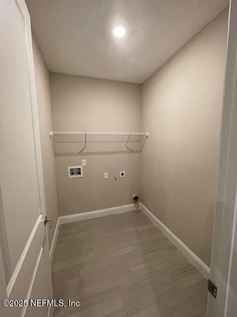 laundry area with hookup for an electric dryer, hookup for a washing machine, a textured ceiling, and wood-type flooring