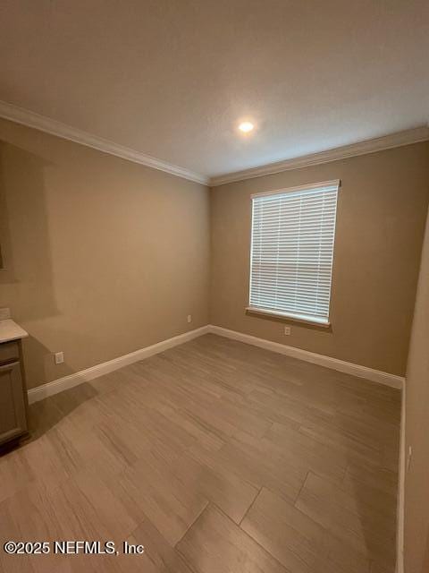 spare room featuring crown molding and light hardwood / wood-style flooring