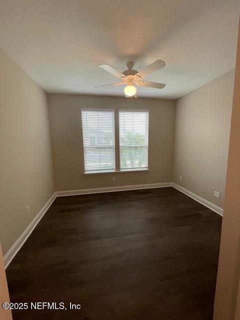 spare room featuring ceiling fan and dark wood-type flooring