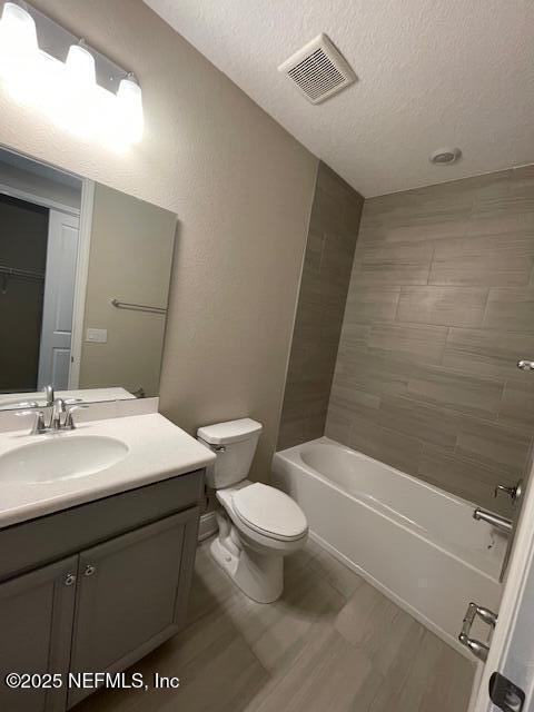 full bathroom with vanity, a textured ceiling, hardwood / wood-style flooring, and toilet