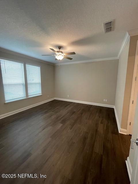 empty room featuring a textured ceiling, dark wood-type flooring, ceiling fan, and ornamental molding