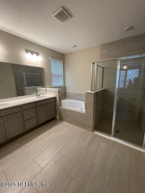 bathroom featuring vanity, a textured ceiling, and shower with separate bathtub