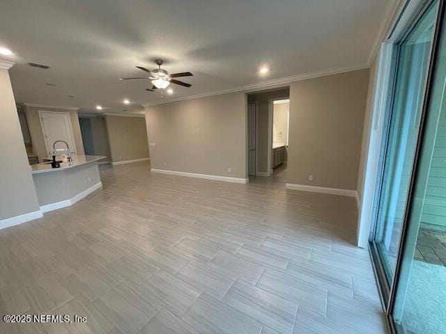 unfurnished living room with ceiling fan and ornamental molding