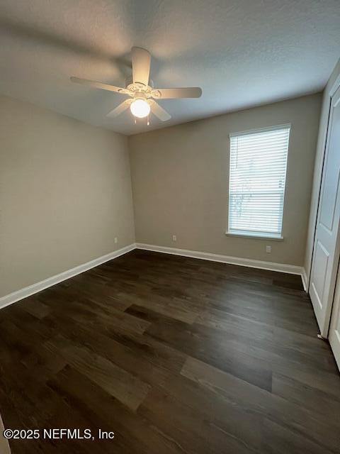 spare room featuring ceiling fan and dark wood-type flooring