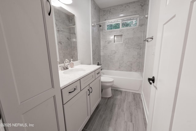 full bathroom featuring vanity, wood-type flooring, tiled shower / bath combo, and toilet